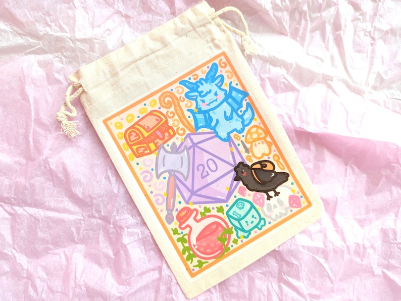 May include: A white drawstring bag with a colorful illustration of a 20-sided die, a dragon, a chest, an axe, a potion, a crow, and a mushroom. The bag is on a pink and white textured surface.