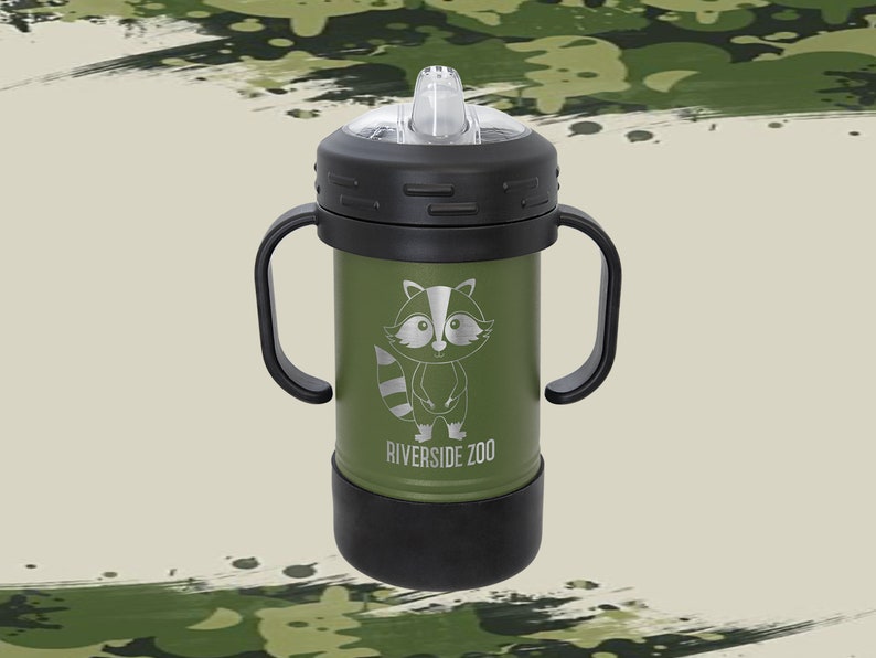 Może przedstawiać: Zielony kubek ze stali nierdzewnej z czarnymi uchwytami i czarną pokrywką. Kubek przedstawia kresk&oacute;wkowego szopa pracza i napis "Riverside Zoo".