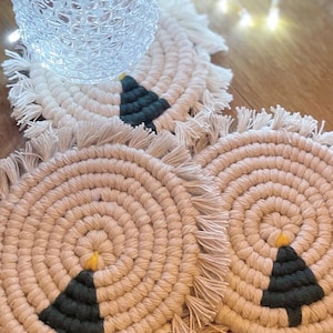 Puede incluir: Tres posavasos redondos de crochet con borde de flecos. Cada posavasos presenta un diseño de árbol de Navidad verde con una estrella amarilla en la parte superior.