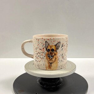 A ceramic mug featuring a detailed German Shepherd portrait stands on a pedestal.
