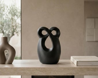 Urna funerária moderna com design escultural infinito em cerâmica resistente.