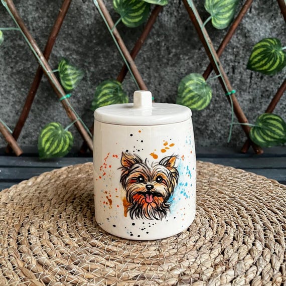 A hand-PAINTED pet urn — an artist literally puts your dog or cat's portrait on their own urn, turning a memorial into a one-of-a-kind work of art; 13 favorites backs up the demand.