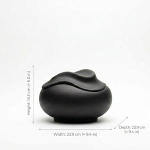 Pode incluir: Um recipiente de cer&acirc;mica preto fosco com tampa. O recipiente &eacute; redondo com uma tampa ondulada. A largura e a profundidade s&atilde;o de 23,9 cm, e a altura &eacute; de 15,3 cm.