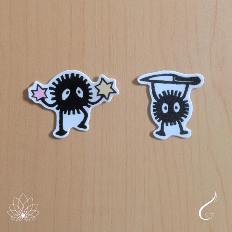 May include: Two die-cut stickers featuring black soot sprites. The left sticker shows a round, spiky black creature holding a pink star and a yellow star. The right sticker depicts a similar black creature holding a long, thin knife above its head.