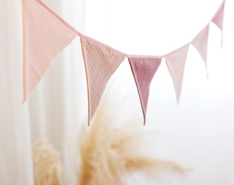 May include: A pink and white fabric bunting with triangular flags hanging from a white background.