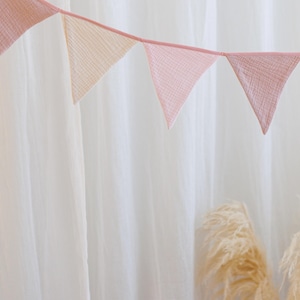 May include: A pink and cream fabric bunting with triangular flags hanging against a white background.