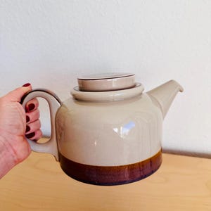 Può includere: Un set di tre tazze in ceramica con finitura opaca e macchiettata. Le tazze sono nei toni del crema, marrone chiaro e marrone scuro. Ogni tazza ha un design semplice e minimalista e un manico arrotondato.