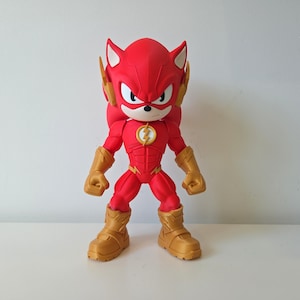 May include: A red action figure of a hedgehog-like character in a Flash-inspired costume. The figure has gold-coloured gloves, boots, and ear accents. A yellow lightning bolt emblem is on the chest. The figure is posed with arms at its sides.