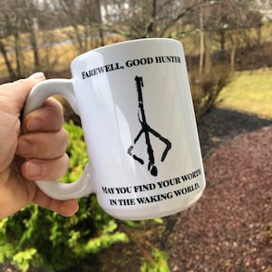 May include: White ceramic mug with a black graphic of a symbol and the text "Farewell, Good Hunter. May you find your worth in the waking world."