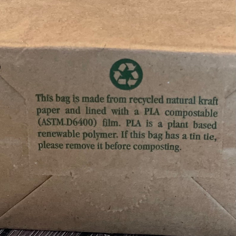 May include: A brown paper bag with a green recycling symbol and text that reads: "This bag is made from recycled natural kraft paper and lined with a PLA compostable (ASTM D6400) film. PLA is a plant based renewable polymer. If this bag has a tin tie, please remove it before composting."