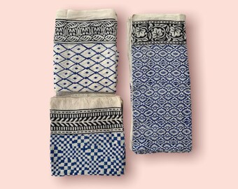 May include: Three white cotton tea towels with blue and black block printed patterns. The patterns include geometric designs, floral motifs, and a border.