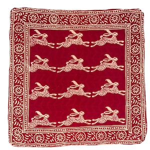 May include: A red cotton fabric square with a white border and a repeating pattern of white rabbits running. The border has a floral design.