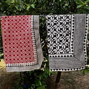 K&ouml;nnte beinhalten: Zwei Stoffquadrate mit schwarzen und wei&szlig;en geometrischen Mustern. Ein Quadrat hat einen roten Hintergrund mit wei&szlig;en Kreisen und einem schwarzen Rand. Das andere Quadrat hat einen wei&szlig;en Hintergrund mit schwarzen geometrischen Formen und einem schwarzen Rand.