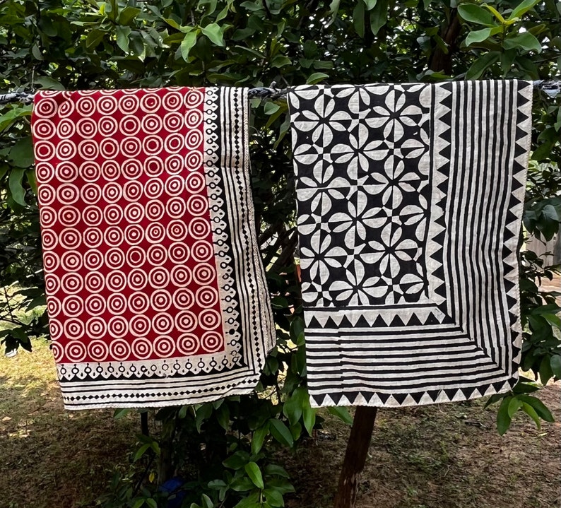 K&ouml;nnte beinhalten: Zwei Stoffquadrate mit schwarzen und wei&szlig;en geometrischen Mustern. Ein Quadrat hat einen roten Hintergrund mit wei&szlig;en Kreisen und einem schwarzen Rand. Das andere Quadrat hat einen wei&szlig;en Hintergrund mit schwarzen geometrischen Formen und einem schwarzen Rand.