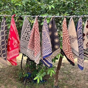 K&ouml;nnte beinhalten: Neun bunte, gemusterte Stoffquadrate h&auml;ngen an einer W&auml;scheleine. Die Quadrate sind aus Baumwolle und haben verschiedene Muster, darunter florale, geometrische und abstrakte Muster. Die Quadrate sind alle unterschiedlich gro&szlig; und geformt.