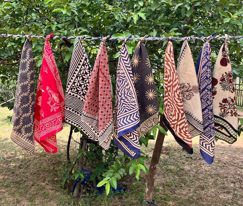 K&ouml;nnte beinhalten: Neun bunte, gemusterte Stoffquadrate h&auml;ngen an einer W&auml;scheleine. Die Quadrate sind aus Baumwolle und haben verschiedene Muster, darunter florale, geometrische und abstrakte Muster. Die Quadrate sind alle unterschiedlich gro&szlig; und geformt.