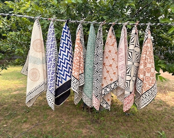 May include: Nine different patterned fabric squares hang on a clothesline. The squares are all white with various black, blue, green, and brown patterns.