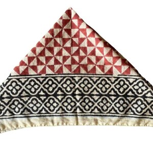 K&ouml;nnte beinhalten: Ein dreieckiges Baumwollbandana mit einem roten und wei&szlig;en geometrischen Muster auf der oberen H&auml;lfte und einem schwarzen und wei&szlig;en geometrischen Muster auf der unteren H&auml;lfte.