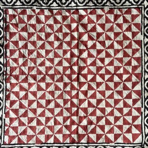 K&ouml;nnte beinhalten: Ein rot-wei&szlig; gemusterter Stoff mit einem schwarz-wei&szlig;en Rand. Der Stoff hat ein geometrisches Muster mit sich wiederholenden Dreiecken.