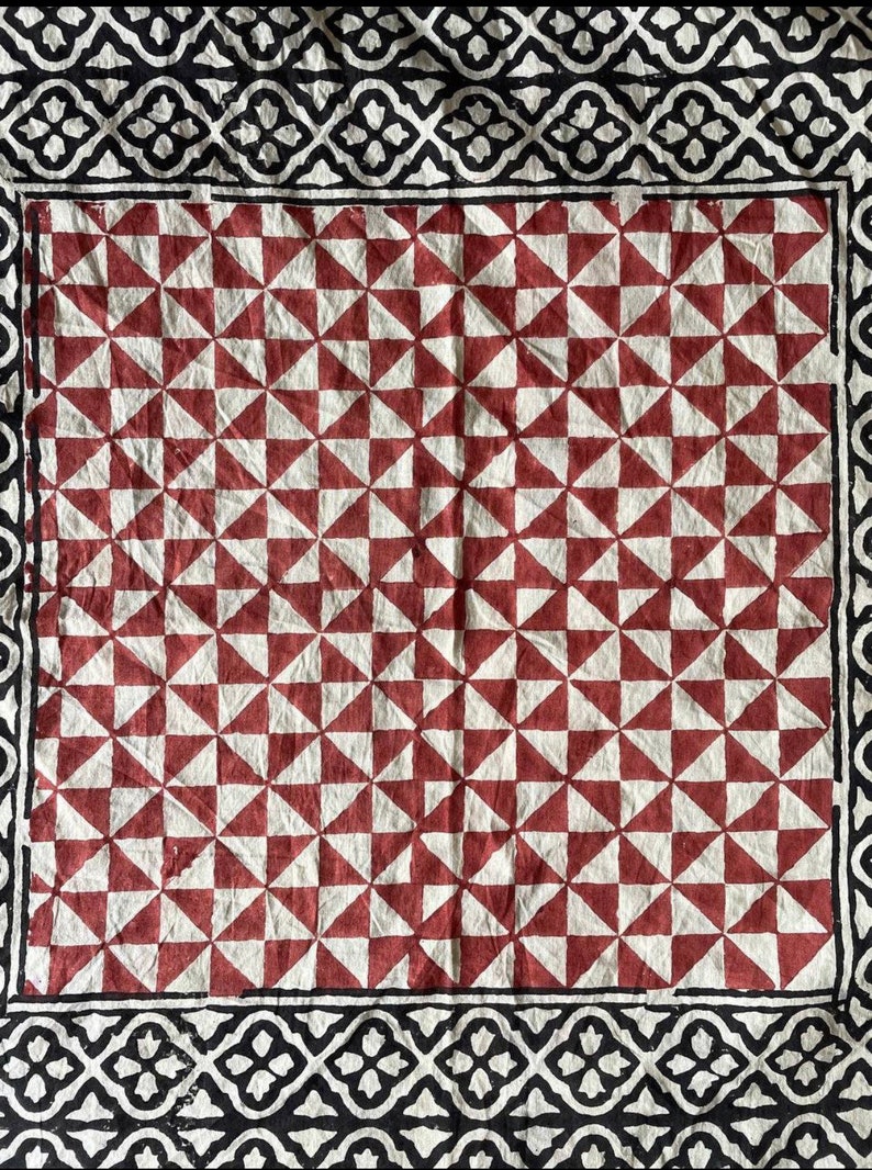 K&ouml;nnte beinhalten: Ein rot-wei&szlig; gemusterter Stoff mit einem schwarz-wei&szlig;en Rand. Der Stoff hat ein geometrisches Muster mit sich wiederholenden Dreiecken.