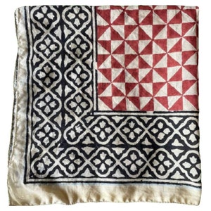 K&ouml;nnte beinhalten: Ein quadratischer Baumwollschal mit einem geometrischen Muster in Schwarz, Wei&szlig; und Rot. Der Schal hat einen Rand aus schwarzen und wei&szlig;en geometrischen Mustern, einen Mittelteil aus roten und wei&szlig;en Dreiecken und einen unteren Teil aus schwarzen und wei&szlig;en geometrischen Mustern.