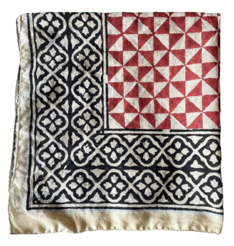 K&ouml;nnte beinhalten: Ein quadratischer Baumwollschal mit einem geometrischen Muster in Schwarz, Wei&szlig; und Rot. Der Schal hat einen Rand aus schwarzen und wei&szlig;en geometrischen Mustern, einen Mittelteil aus roten und wei&szlig;en Dreiecken und einen unteren Teil aus schwarzen und wei&szlig;en geometrischen Mustern.