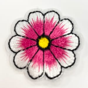 May include: An embroidered flower patch in pink and white with a yellow centre. The flower has a black outline.