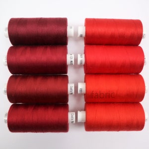 May include: Six spools of thread, three red and three burgundy, with white labels. The labels have text that reads "RBF", "£949 1000", "RBEJ", "In 120 M0055", "Coats No", and "Coats Mo".