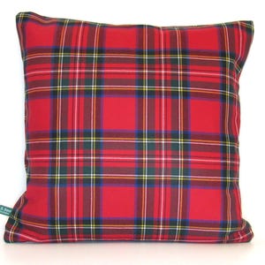 May include: Square decorative pillow with a red plaid pattern. The pillow features a classic tartan design with intersecting lines in red, white, green, yellow, and blue. A small green tag is visible on the lower left corner.
