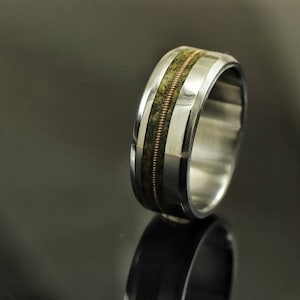 May include: A silver ring with a green and copper inlay. The ring is wide and has a beveled edge.