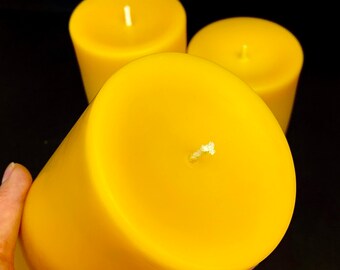 May include: Three yellow pillar candles with white wicks. The candles are arranged in a pyramid shape.