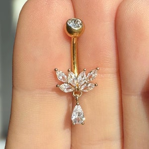 May include: Gold belly button ring with a clear crystal flower design and a teardrop-shaped crystal dangle.