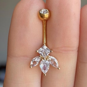 May include: Gold belly button ring with a clear crystal center and five clear crystal petals.