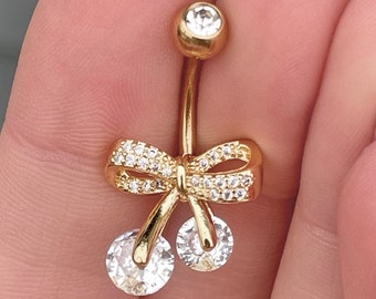 May include: Gold belly button ring with a clear crystal bow and two clear crystal accents.