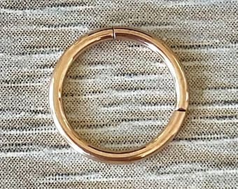 May include: A gold-colored seamless ring for body piercing.