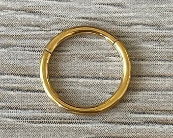 May include: A gold-colored hoop earring with a seamless design. The hoop is made of metal and is a simple, classic style.