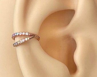 May include: A close-up of a person's ear with a rose gold double hoop earring with clear and iridescent stones.