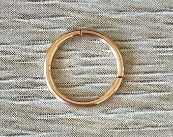 May include: A gold-colored seamless hoop earring. The hoop is made of metal and has a smooth, polished finish.
