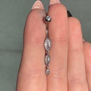 Puede incluir: Un piercing de cuerpo de plata con tres piedras ovaladas transparentes. Las piedras est&aacute;n engastadas en un engaste de bisel de plata.