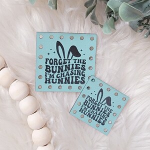 May include: Two light blue square-shaped fabric patches with a bunny ear design and the text "FORGET THE BUNNIES I'M CHASING HUNNIES".