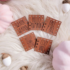 May include: Five brown leather tags with white text. The tags have a dotted pattern around the edges. The text on the tags reads "Sweater Weather", "Hello Pumpkin", "Fall Y'all", "Hello Gourd-Geous", and "Cozy Vibes".
