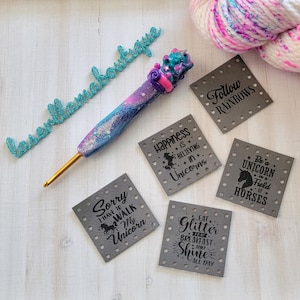 May include: Five gray fabric patches with black text and unicorn designs. The text on the patches reads "Happiness is believing in unicorns", "Sorry I have to walk my unicorn", "Eat glitter for breakfast and shine all day", "Follow rainbows", and "Be a unicorn in a field of horses".