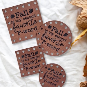 May include: Four brown leather coasters with the text "Fall is my second favorite F-word". The coasters are in square and round shapes, with small holes around the edges. Autumn leaves and pinecones are in the background.