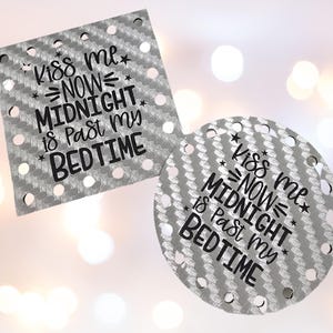 May include: Two gray, textured, decorative pieces with the text "Kiss me NOW MIDNIGHT is Past my BEDTIME" in black. One piece is square, the other is round, both with evenly spaced holes.