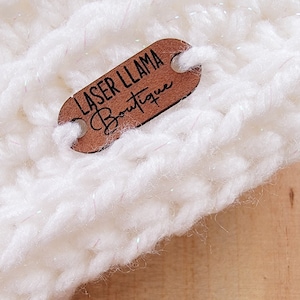 May include: White crocheted hat with a brown wooden tag that says "Laser Llama Boutique".