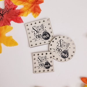 May include: Three wooden signs with a black and white design. The signs say "I put a spell on you" with a cauldron and stars. The signs are on a white background with candy corn.
