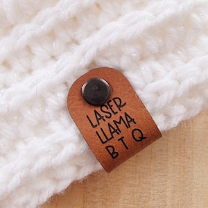 May include: White crocheted hat with a brown leather tag that says "Laser Llama BBQ".