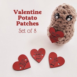 May include: Set of eight red felt heart-shaped patches with different Valentine's Day messages. The patches have two holes for sewing. A crocheted brown potato character holds a red felt heart with the message "I only have eyes for you!"