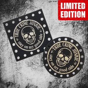May include: Two black leather patches with gold lettering and a skull design. The text on the patches reads "True Crime Junkie - Stay on my good side". The patches are labeled "Limited Edition".