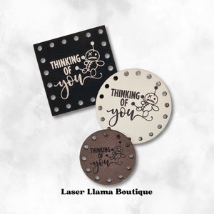 May include: Three wooden tags with the text "Thinking of you" and a small voodoo doll graphic. The tags are in black, white, and brown.